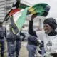Mulher sul-africana protesta com a bandeira da África do Sul enquanto policiais acompanham manifestação durante tensão causada por ultimato de grupos anti-imigração.